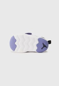 Semelle de sneaker en blanc et violet, présentant des motifs de semelle en vagues et un logo noir. Matériau doux avec une finition texturée sur la partie violette.