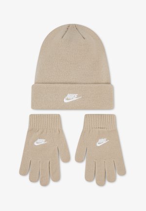 Béžová pletená zimná čiapka Nike a zodpovedajúce rukavice, obe s bielym vyšitým logom Nike, zobrazené na bielom pozadí.