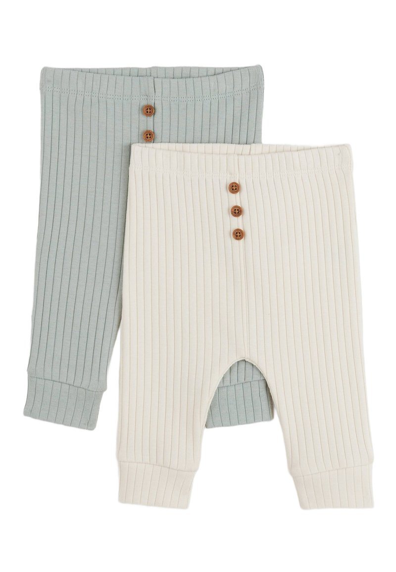 Deux paires de pantalons côtelés : une en vert doux avec trois boutons marron, l'autre en crème avec des boutons similaires et une découpe sur la jambe.