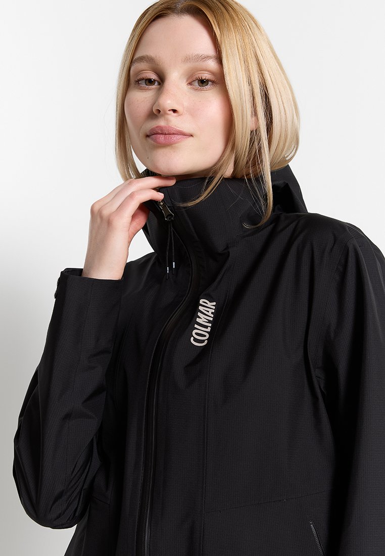 Giacca impermeabile nera con colletto alto, chiusura con zip e tasche laterali. Il tessuto presenta una texture sottile con un dettaglio del logo sulla parte anteriore.