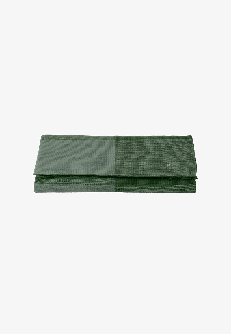 Tissu rectangulaire plié dans différentes nuances de vert. Présente des côtes texturées et un motif subtil. Petit logo sur un côté.