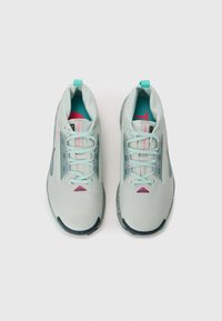 Light grey athletic shoes with mesh upper, turquoise laces, pink accents, and textured sole. Features a triangular design detail near the toe.