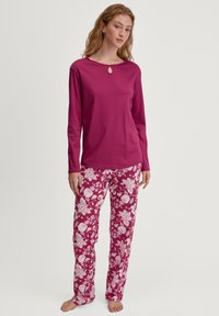 Langdurige mouwen, magenta top met een keyhole halslijn, gecombineerd met roze bloemenpatroon broek. Zachte stof, ontspannen pasvorm en full-length ontwerp.