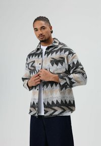 Geweven flanellen overhemd met een geometrisch patroon in zwart, grijs en beige. Drukknoopsluiting, borstzak, comfortabele pasvorm en lange mouwen.