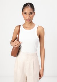 Top de tirantes blanco acanalado, pantalones beige de tiro alto, bolso de cuero marrón con una correa delgada, textura suave, diseño ajustado, estilo minimalista.