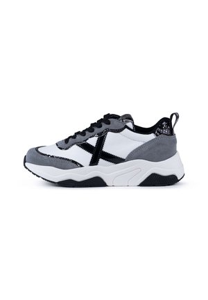 Sneaker sportivo con una combinazione di suede grigio, pelle bianca e dettagli neri. Suola spessa con suola testurizzata per una migliore aderenza.