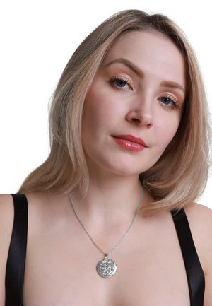 Silver pendant necklace with a textured, floral design, attached to a thin, twisted chain. Model wears a black top, showing the necklace clearly.