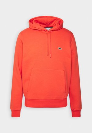 Sudadera con capucha de color naranja brillante con bolsillo canguro frontal y pequeño logo verde de cocodrilo en el pecho izquierdo.