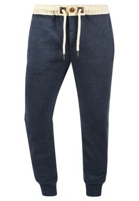 Navy jogger pants made of soft fabric, featuring a cream drawstring, elastic waistband, and ribbed cuffs. Minimalist design with no additional patterns.