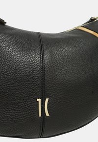 Borsa a mano in pelle nera con superficie testurizzata, forma curva, hardware color oro e zip visibile. Presenta un distintivo accentuato del logo.