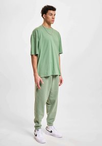 Groene oversized t-shirt met ronde hals, gecombineerd met bijpassende tapering joggers. Outfit gemaakt van zachte katoenen stof, met elastische manchetten.