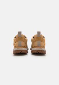 Zapatillas marrones con material de malla, detalles grises y un talón reforzado. Suela de tracción y tirador en la parte trasera para ponerlas fácilmente.