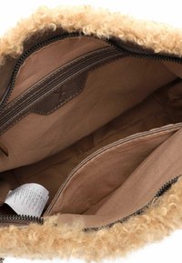 Brūna auduma soma ar mīkstu, cirtainu brūnganu kažokādu. Iekļauj rāvējslēdzēja kabatu un plašu iekšpusi ar papildu auduma nodalījumiem.