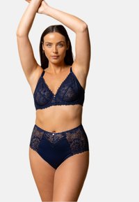 Un bralette en dentelle marine et des culottes taille haute présentent des bords festonnés et des motifs floraux. Le tissu a une texture douce et lisse avec des accents décoratifs.