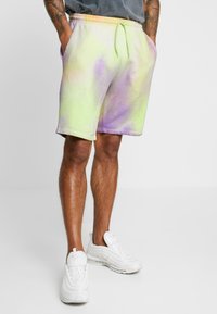 Shorts tie-dye dans des teintes vertes et lavande, fabriqués en coton doux avec une taille élastique et un cordon de serrage. Comprend des poches latérales.