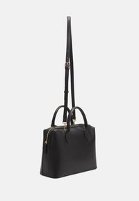 Musta nahkainen käsilaukku, jossa on kaksi yläkahvaa ja irrotettava olkahihna. Varustettu kultaisella vetoketjulla ja sileällä pinnalla. Kompakti muotoilu.