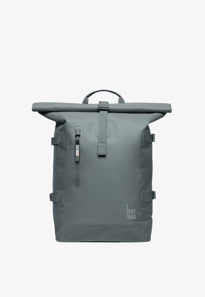 Mochila de roll-top en gris, fabricada con material duradero. Cuenta con un bolsillo frontal con cremallera, correas ajustables y un asa de transporte superior.