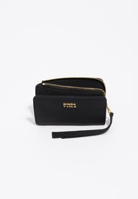 Cartera de cuero negro con cierre de cremallera, herrajes en tono dorado y una correa de muñeca de tela desmontable. Presenta un logotipo en la parte frontal y compartimentos para tarjetas en el interior.