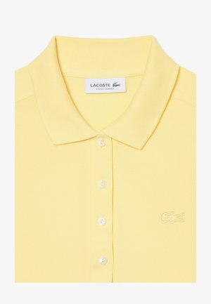 Camiseta polo amarilla ajustada de Lacoste con cuello, cuatro botones y logo bordado de cocodrilo en el pecho izquierdo.