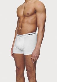 Hvit bomullsboxer med en svart "PEGADOR" logo på midjebåndet, med en tettsittende design og glatt tekstur.