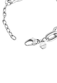 Zilveren kettingarmband met verbonden ovale en ronde schakels, voorzien van een karabijnslot en een hexagonaal label gegraveerd met "BREIL."