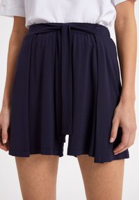 Shorts bleu marine en tissu doux et fluide, dotés d'une ceinture à nouer, d'un design plissé et d'une silhouette décontractée.