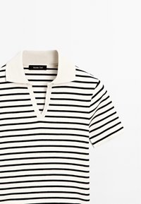 Polo en maille blanche à manches courtes avec des rayures horizontales noires et un col blanc, avec un col en V.