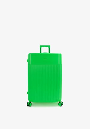 Valise rigide verte brillante avec poignée télescopique étendue et quatre roues doubles multidirectionnelles sur fond blanc.