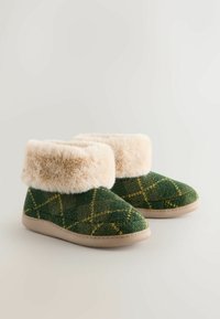 Papuci cu carouri verzi și galbene, cu un manșon din blană sintetică bej și o talpă din cauciuc bej, având un material texturat moale și un design cu tăietură joasă.
