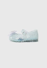Sapato glitter azul claro com bico arredondado, uma tira com fivela redonda e um laço decorativo. Apresenta uma marcação na lateral.