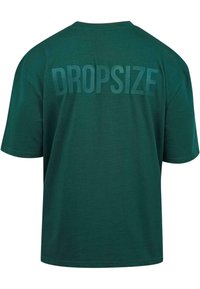 Grünes Baumwoll-T-Shirt, kurze Ärmel, runder Ausschnitt. Auf der Rückseite steht das Wort "DROPSIZE" in großen, strukturierten Buchstaben.