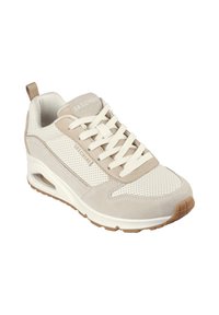 Baskets de sport beige et crème en matériaux suédé et maillés, avec des accents perforés, une semelle en caoutchouc et un col rembourré. Logo "SKECHERS" présent.