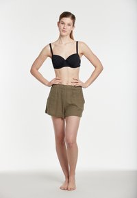 Juodas bikini viršus su minkštais puodeliais ir plonais dirželiais, derinamas su alyvuogių žalios spalvos, tekstūruotomis glaudėmis su elastinga juosmens juosta ir šoninėmis kišenėmis.