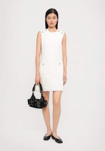 Biała sukienka bez rękawów z teksturowanej tkaniny, z postrzępionym dołem i dwiema przednimi kieszeniami; zestawiona z małą czarną torbą i czarnymi balerinami.