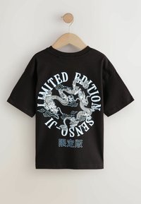 Svart bomullströja med korta ärmar, med en stor vit och blå drakegrafik och texten "LIMITED EDITION" i en cirkulär design.