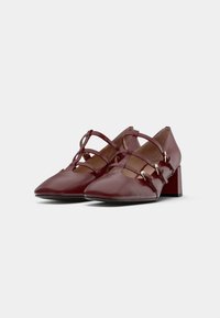 Burgundy leather shoes with a pointed toe, strap detailing, and a block heel. Features gold accents and a smooth texture.
