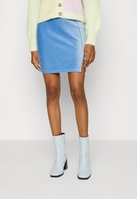 Mini saia de ganga azul clara com uma fenda lateral, combinada com botins azul pálido que têm bico quadrado e salto em bloco.