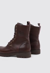 Botas de tobillo de cuero marrón con un acabado texturizado, ojales de metal y suela resistente; presenta una marca en el lateral y lengüetas en la parte posterior.