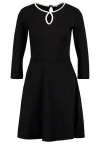 Abito nero con maniche lunghe e gonna svasata. Presenta un collo a chiave bianco e un corpino aderente realizzato in tessuto morbido.