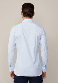Lichtblauw gestreept shirt met lange mouwen, knoopmanchetten en een klassieke kraag. Soepele stof, slim fit en een gegolfde rand.