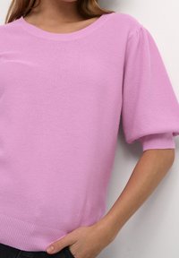 Pull tricoté rose clair avec un col rond, des manches courtes bouffantes et des accents côtelés à l'ourlet et aux poignets, présentant un motif texturé.