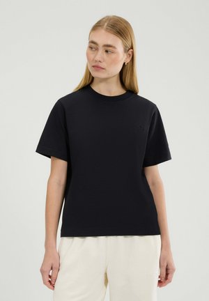 Black cotton t-shirt with short sleeves and a round neckline, featuring a subtle logo detail on the chest. Soft, smooth texture.