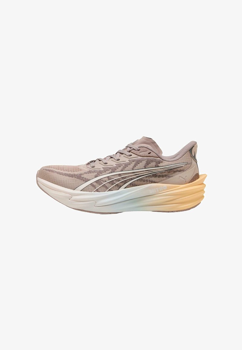 Chaussure de course Puma marron clair avec tige à motif ondulé, semelle épaisse blanche et beige, et logo Puma au talon et sur le côté.