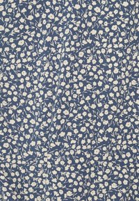 Tissu bleu marine avec un motif floral blanc ; petites fleurs et tiges disposées de manière dense, créant un design organique et texturé.