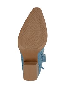 Zapato textil azul con tacón cuadrado, que presenta una suela texturizada y decorada, y una parte inferior de goma marrón para mayor agarre.