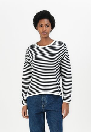 Black and white striped sweater with a rounded neckline and long sleeves, made of soft fabric, paired with high-waisted blue jeans.