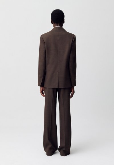 Abito marrone composto da un blazer su misura con colletto a vista e pantaloni a gamba larga coordinati, realizzato in un tessuto morbido con una sottile trama.
