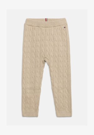 Beige kabelstrikkede bukser med ribbet linning og manchetter, lille logo nær linningen og trikolor stribe detalje på linningen.