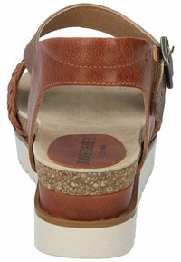 Sandalo in pelle marrone con dettaglio intrecciato, fibbia regolabile, soletta in sughero e suola in gomma bianca. La superficie testurizzata aggiunge interesse visivo.