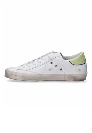 Sneaker in pelle bianca con profilo basso, punta rotonda e accentuazione verde testurizzata sul tallone. Presenta occhielli in metallo e una suola leggermente consumata.